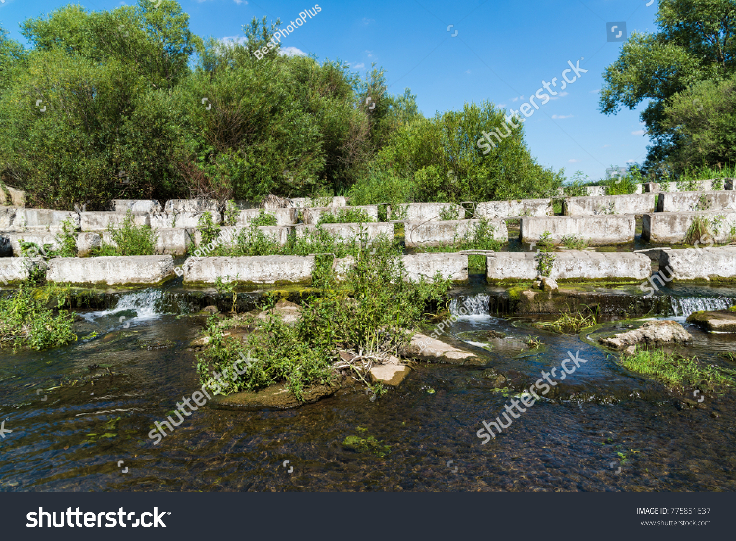 Concrete blocks lying on a small river - dam #775851637