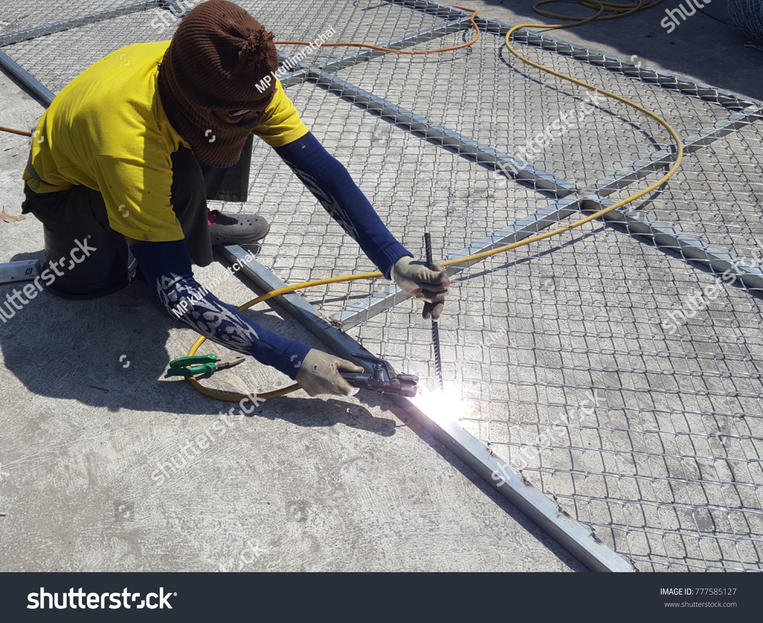 Worker is welding  for Steel wire tie in construction site. for Installation of barbed wire.Wear long gloves with stripes.concept for labor day #777585127