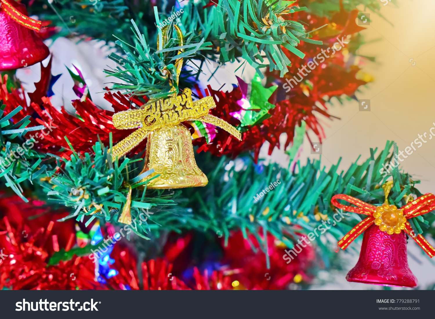 Golden bell hanging on a Christmas tree with a ribbon and golden light as a background. Ideas for Christmas. select focus. close up. #779288791