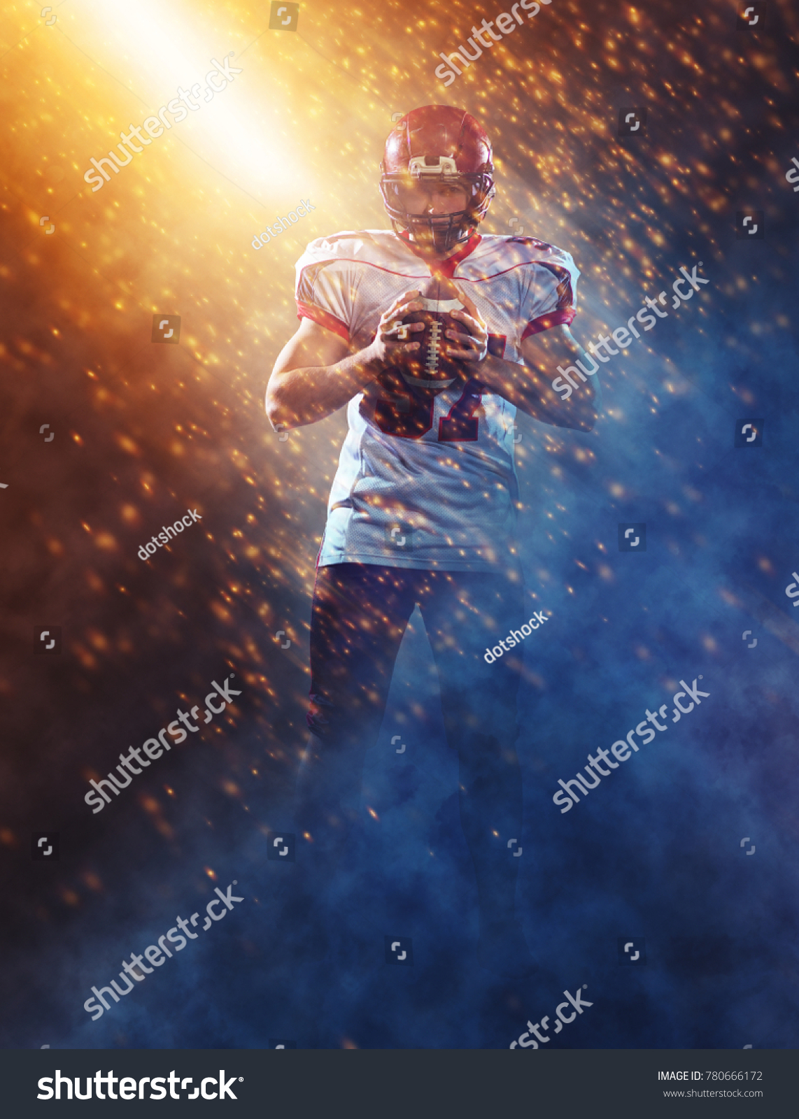 portrait of confident American football player holding ball while standing on the big field with particles effects and lights #780666172