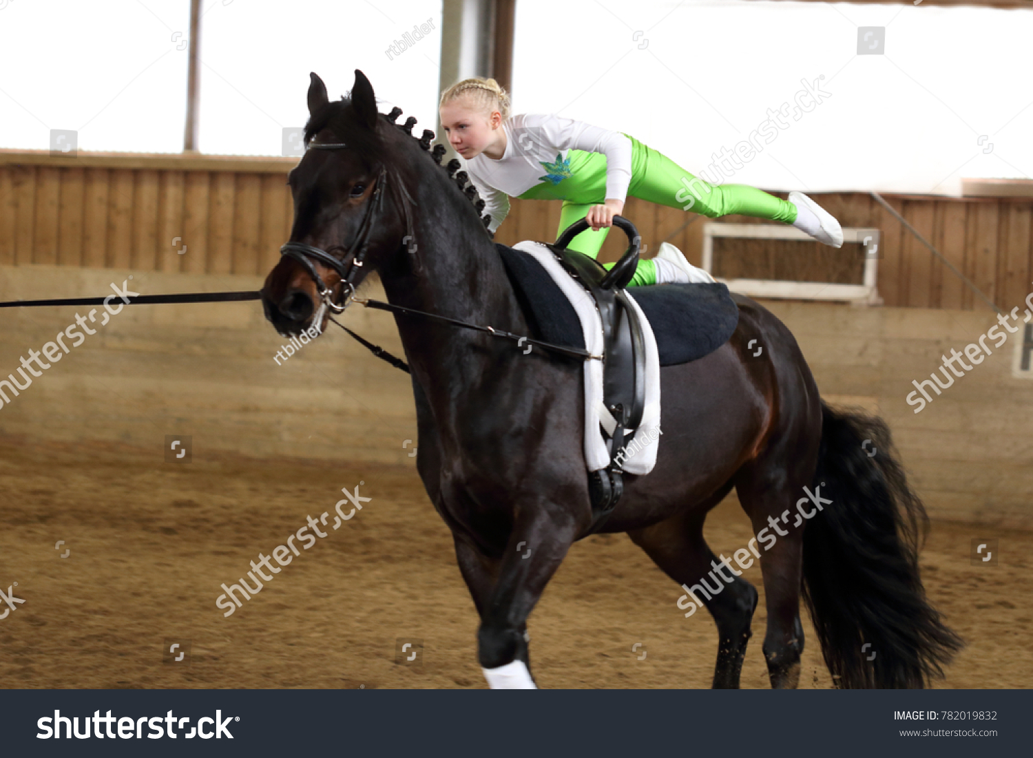 young girl is vaulting on a black horse #782019832