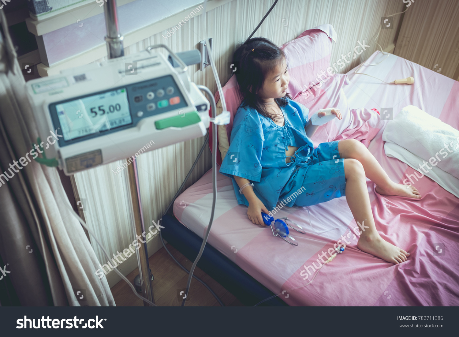 Illness asian girl admitted in hospital with infusion pump feeding IV drip. Shallow depth of field (DOF) child in focus, IV machine out of focus. Health care stories. Vintage film filter effect. #782711386