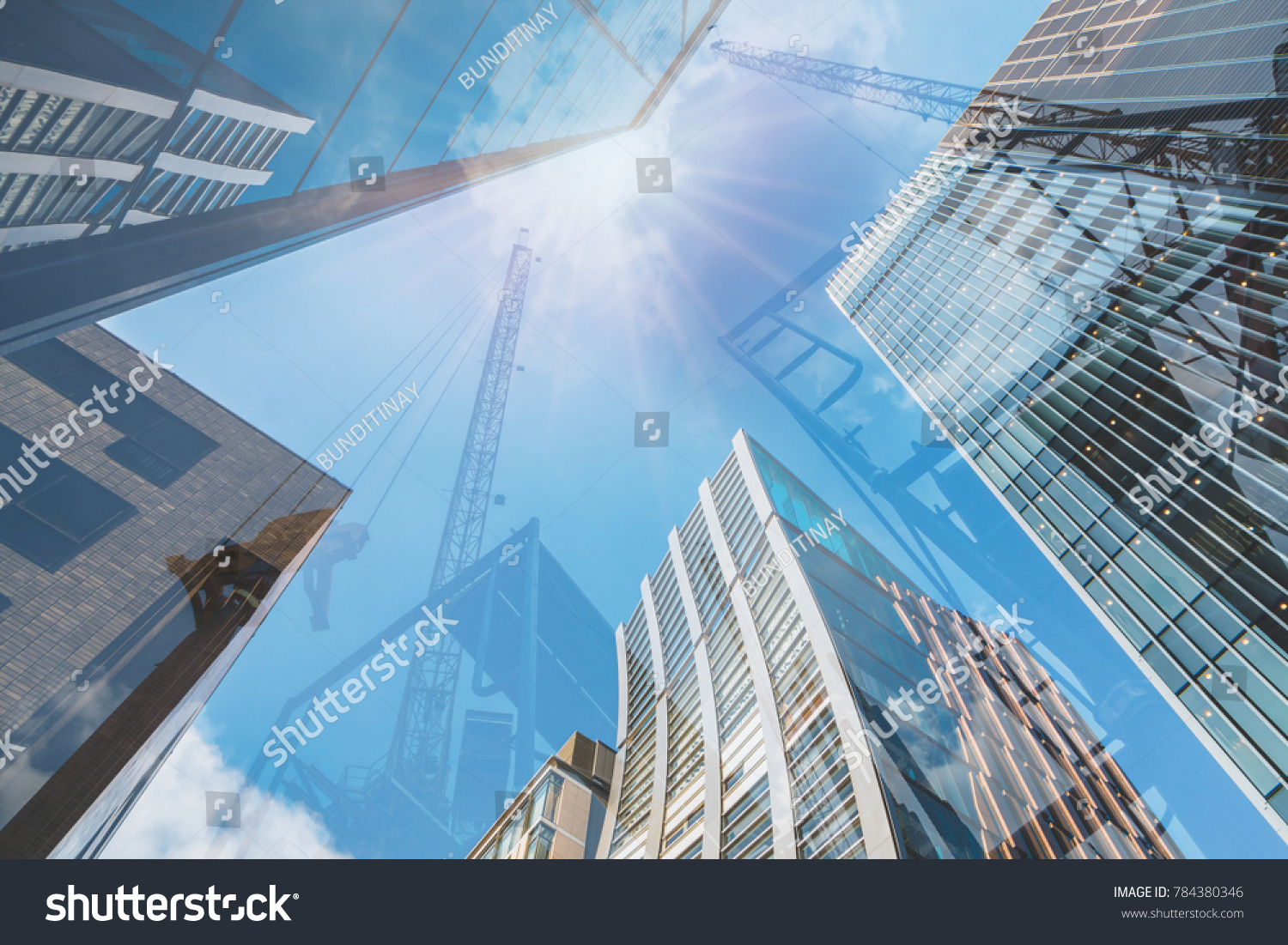 Double exposure of abstract real estate construction site and modern business skyscrapers, high-rise architecture buildings raising to the sky. Concepts of business financial, economics. #784380346