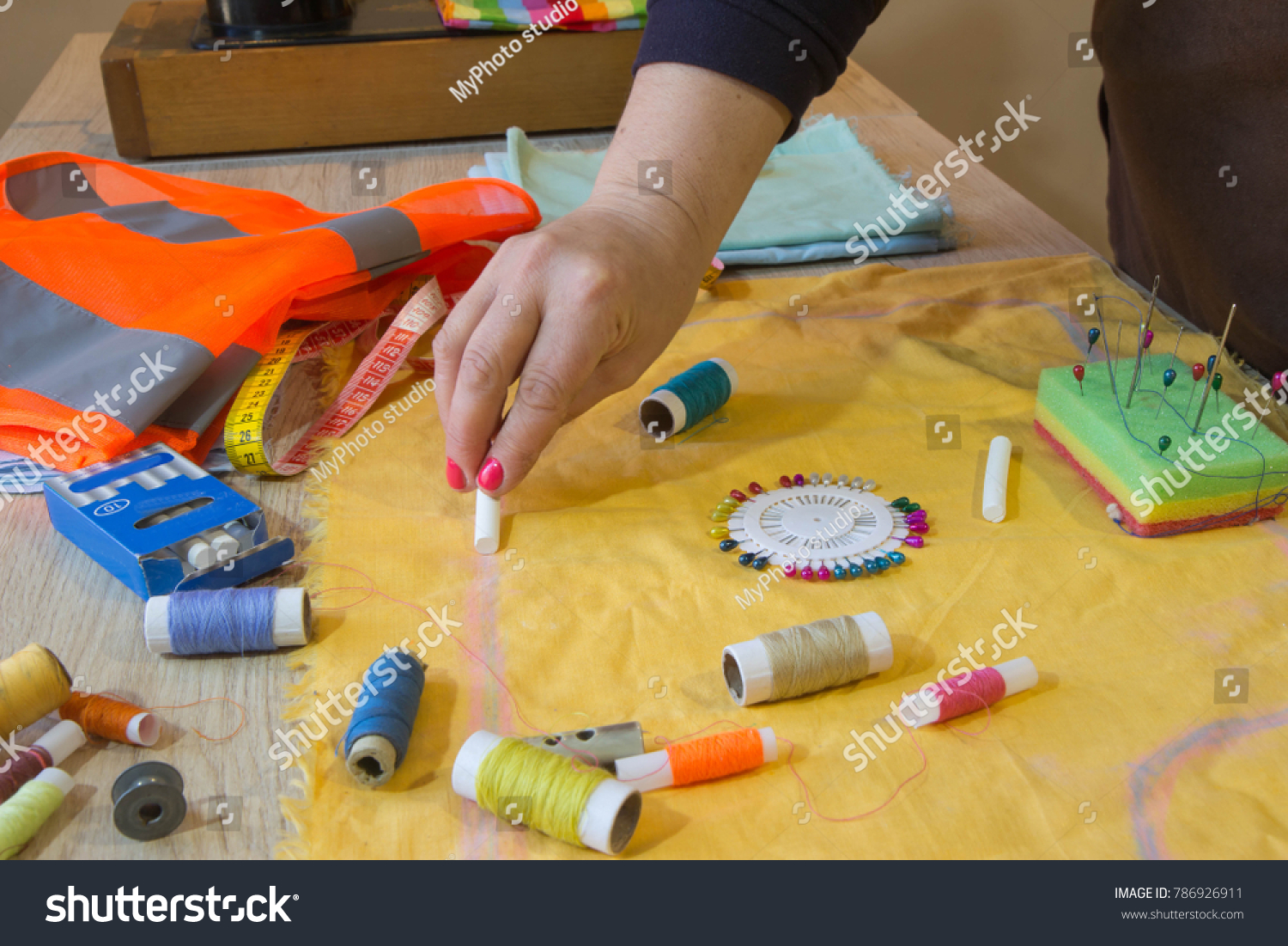 Woman dressmaker drawing tailor pattern with chalk for a clothing on the table. The outline on the fabric painted chalk. Garment industry, tailoring concept #786926911