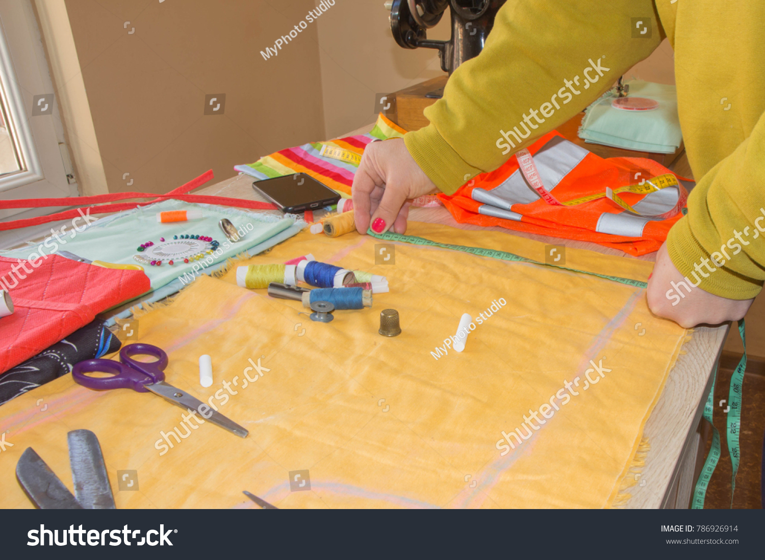 Fashion designer, Woman tailor posing at her workplace with cut fabric, free space on wooden work table. Garment industry, tailoring concept #786926914