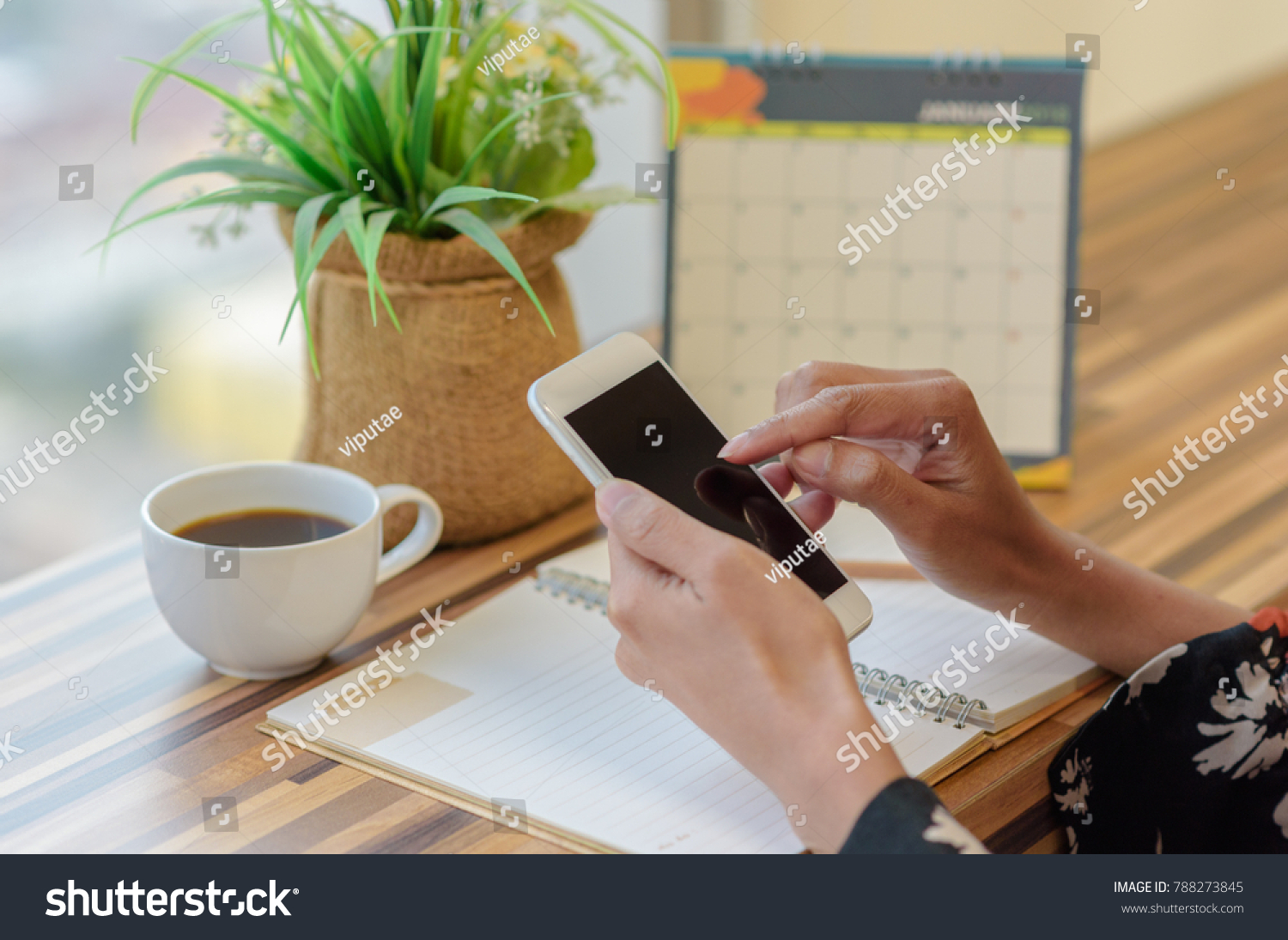Woman holding smartphone to update calendar with notebook pencil diary vase on table with blurred calendar. planning scheduling agenda and event for 2018. Calendar and Planning concept. #788273845