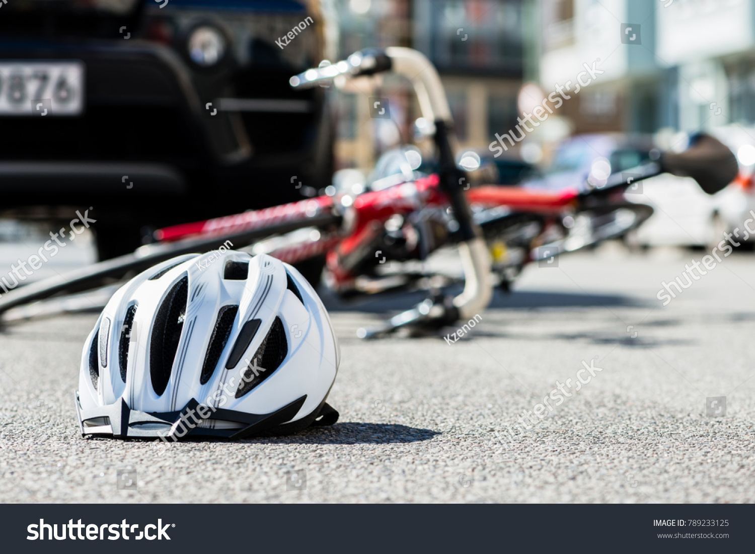 Close-up of a bicycling helmet fallen on the asphalt  next to a bicycle after car accident on the street in the city #789233125