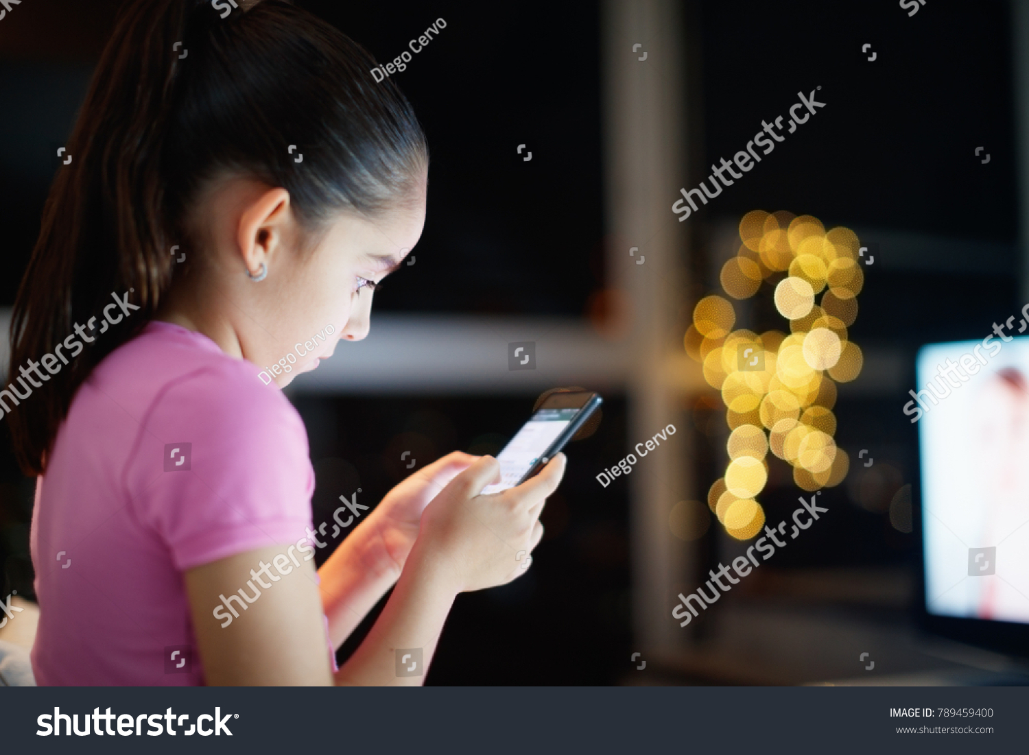 Young people and youth problems. Preteen girl left alone at home, sends text messages with phone to friends. Concept of potential victim of cyber bulling and absence of parental control #789459400