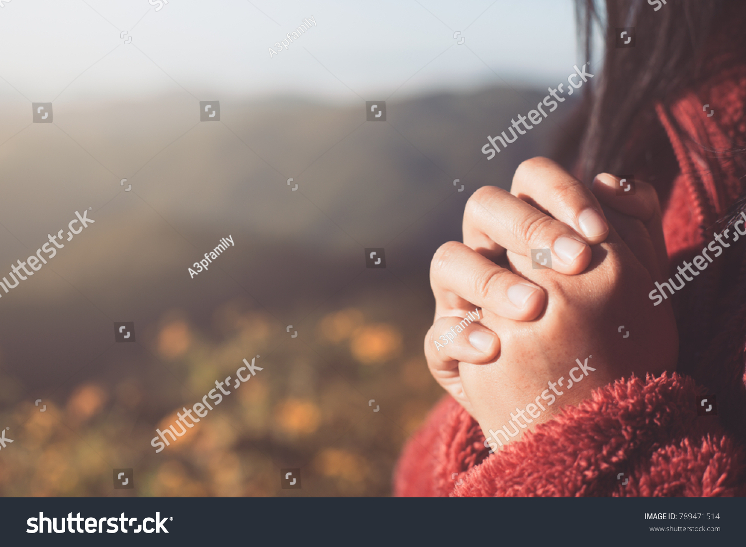Woman hands folded in prayer in beautiful nature background with sunlight in vintage color tone #789471514