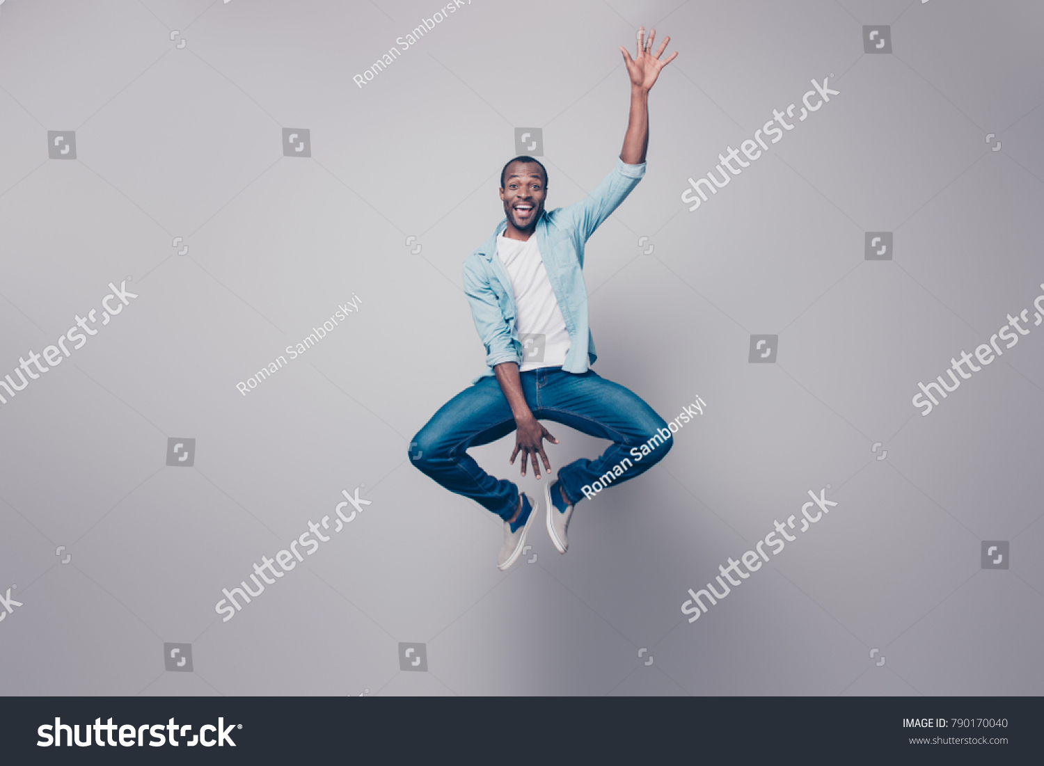 Full-size full-length portrait of cheerful handsome joyful excited delightful impressed surprised afro guy wearing casual denim jeans clothing jumping up, isolated on gray background #790170040