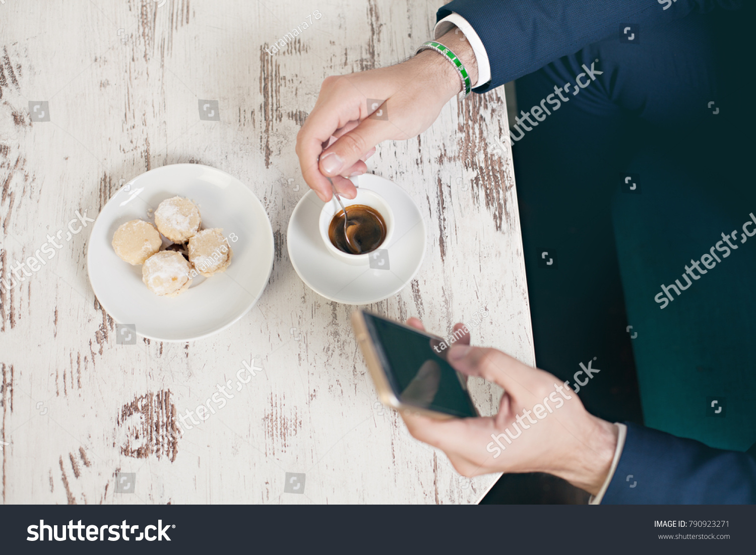 Top view of young  man using mobile phone sitting by cafe table drinking coffee and eating cookies #790923271