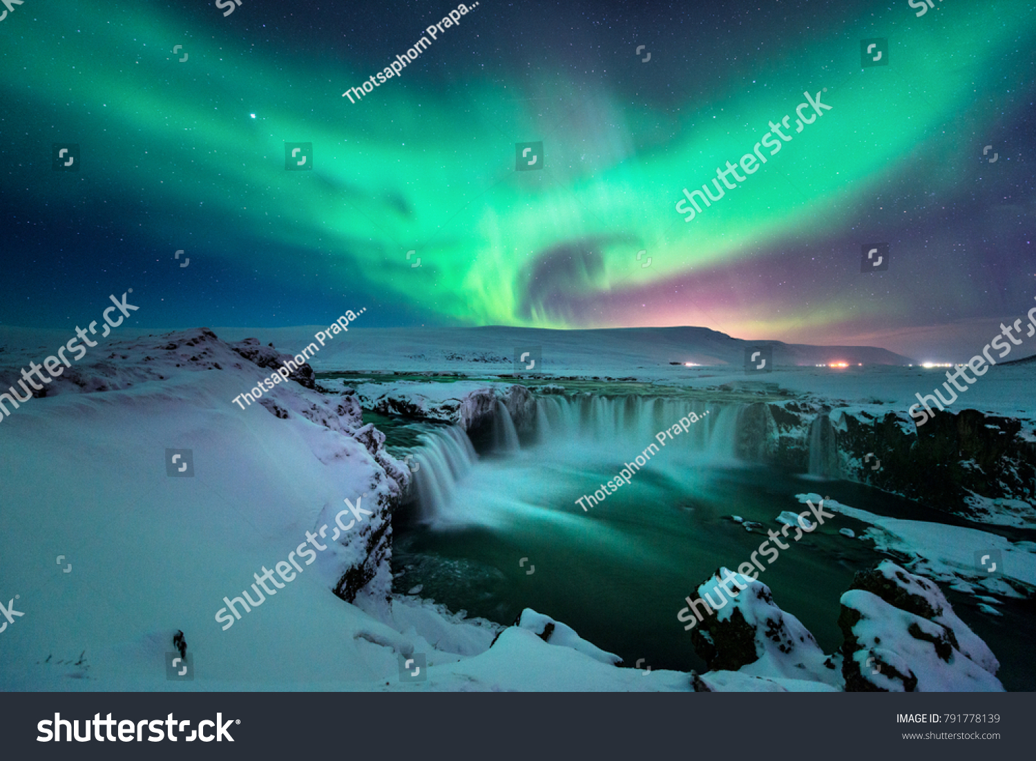 A stunning glowing aurora shape like phoenix bird appears above the landscape of Godafoss waterfall in winter Iceland #791778139