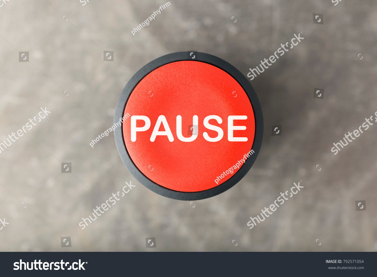 Overhead of a red pause push button over a blurred gray background #792571054
