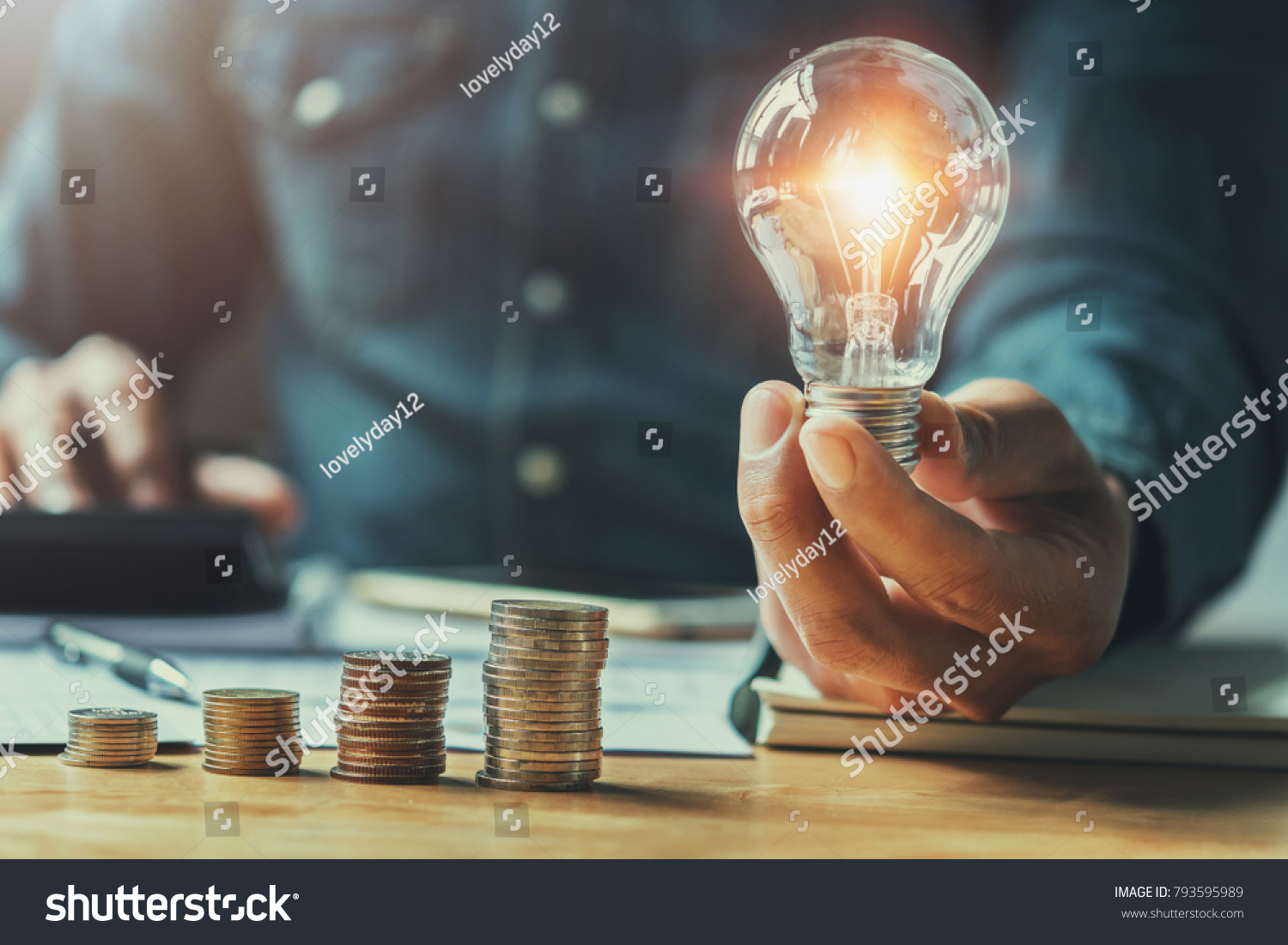 business man hand holding lightbulb with using calculator to calculate and money stack. idea saving energy and accounting finance in office concept #793595989