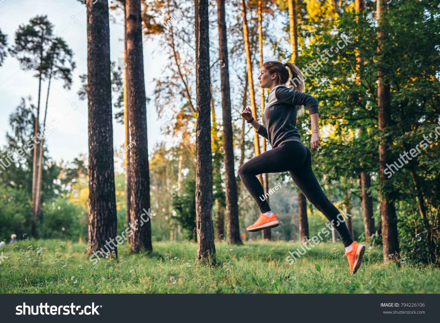 Young female athlete jogging in forest. Jogger doing morning physical training. #794226106