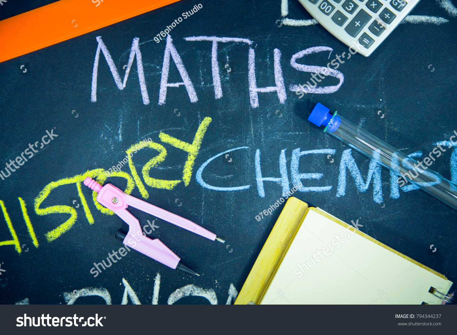 Education concept: Names of school subjects inscribed on a black chalkboard with colored chalks and stationary, close up, top view #794344237