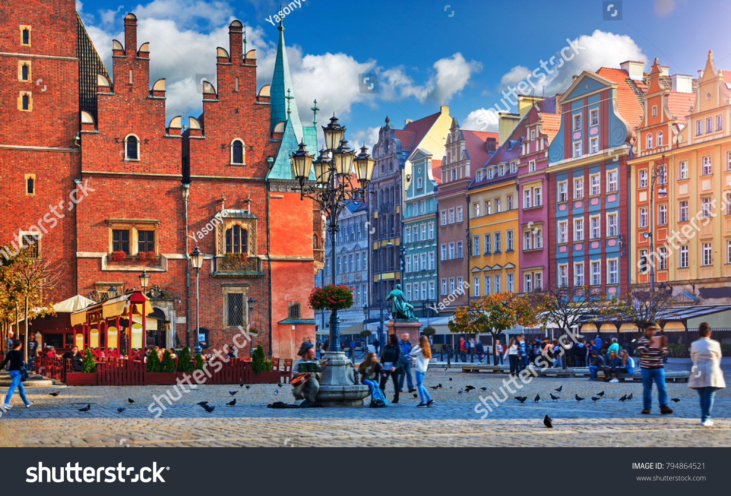 Wroclaw central market square with old colourful houses, street lamp and walking tourists people at evening sunset sunshine. #794864521