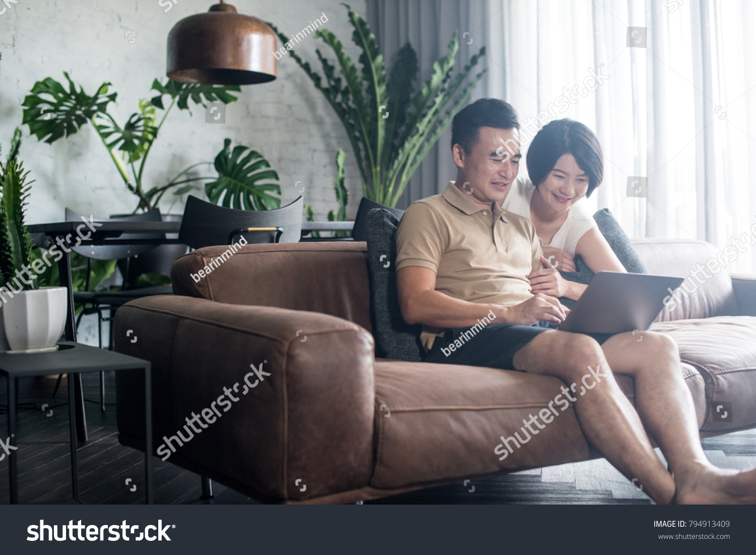 Happy Asian couple looking at the computer together at home. #794913409