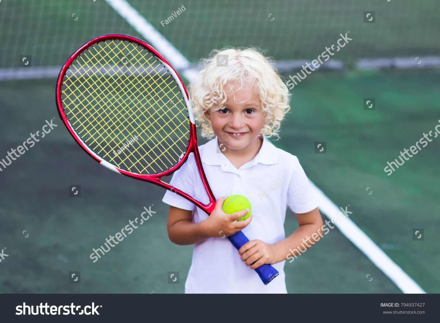 Child playing tennis on outdoor court. Little boy with tennis racket and ball in sport club. Active exercise for kids. Summer activities for children. Training for young kid. Child learning to play. #794937427