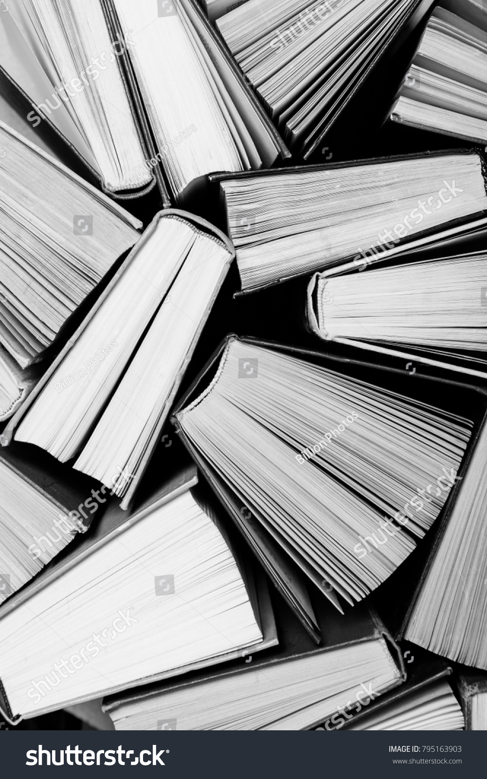 A black and white image of hardback books or text books from above. Books and reading are essential for self improvement, gaining knowledge and success in our careers, business and personal lives #795163903