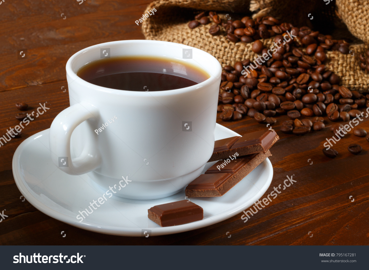 A white pitcher, coffee beans, chocolate and a coffee bag with a wooden background #795167281