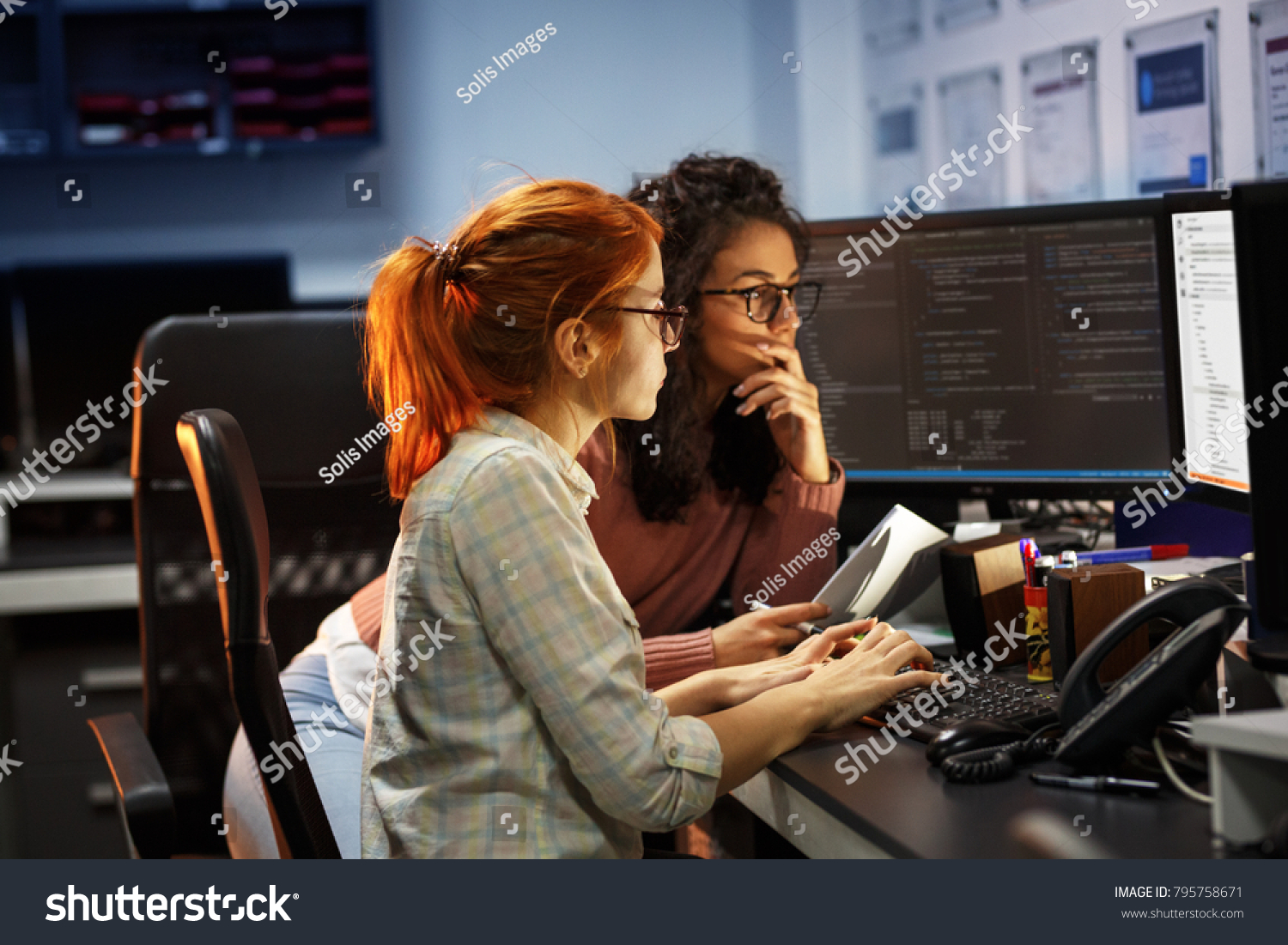 Two female programmers working on new project.They working late at night at the office. #795758671