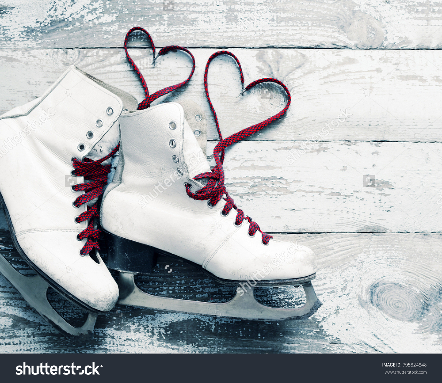 Old white skates for figure skating with a hearts of laces on a vintage wooden surface. Concept of love. #795824848