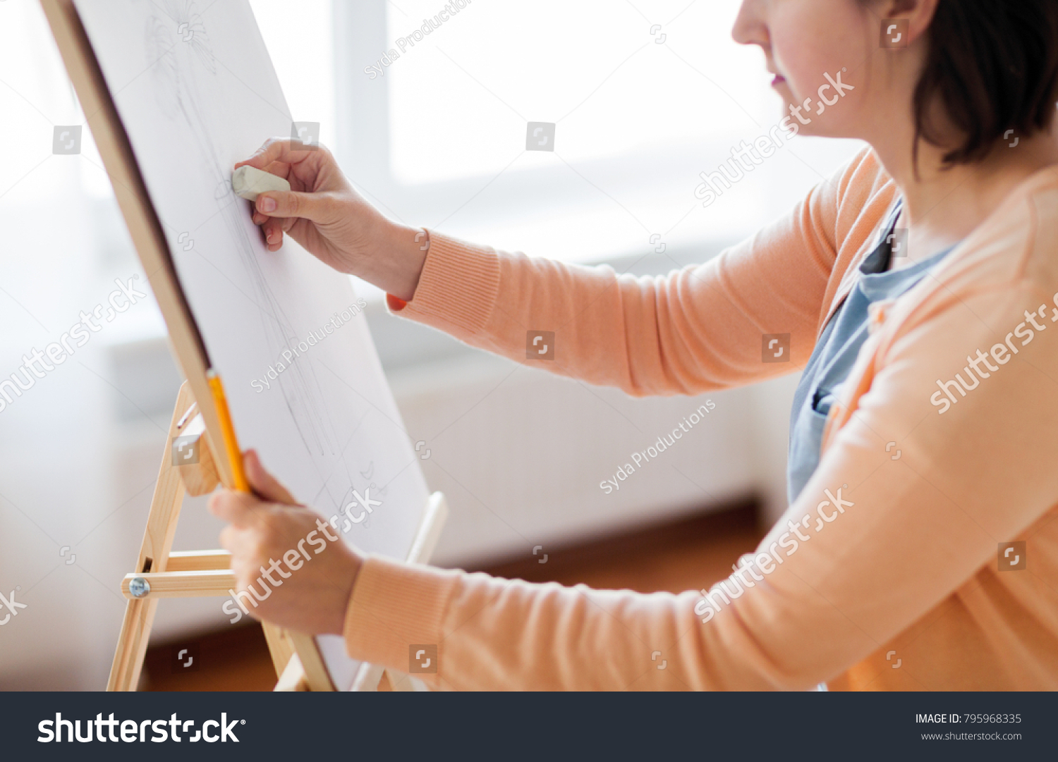 art, creativity and people concept - artist with eraser and still life picture of flower in vase on easel at studio #795968335