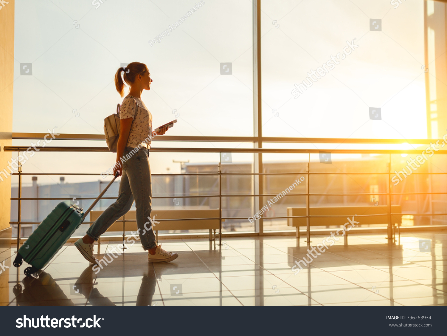young woman goes  at airport  at window  with a suitcase waiting for  plane
 #796263934