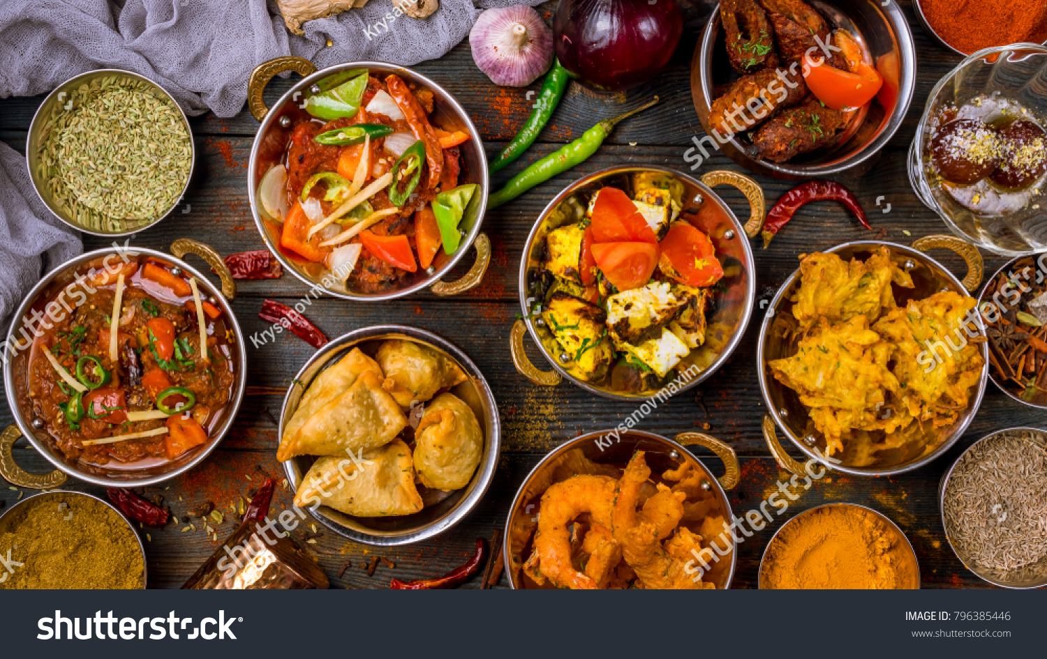 Assorted indian food set on wooden background. Dishes and appetisers of indeed cuisine, rice, lentils, paneer, samosa, spices, masala. Bowls and plates with indian food top view #796385446
