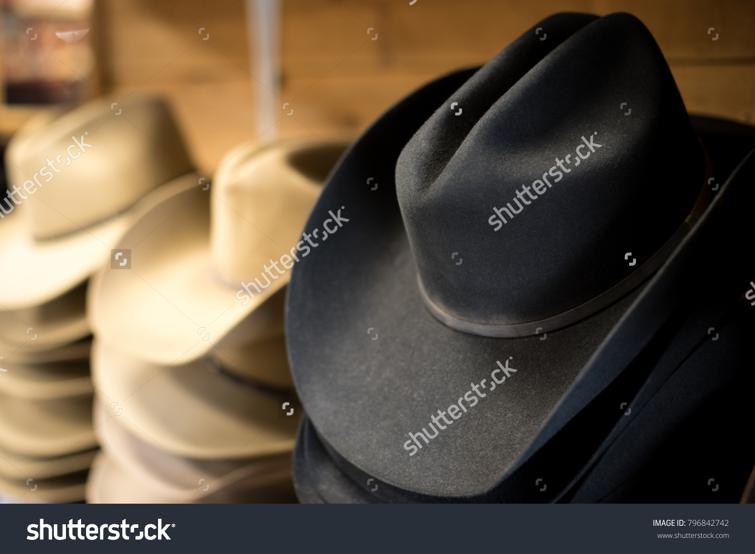 Side perspective close up on a stack of traditional black felt cowboy hats, with wide western brims #796842742