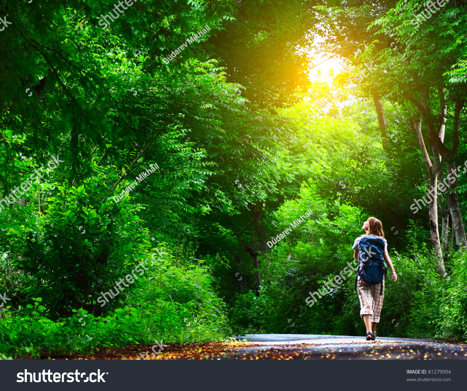 Young woman walking on green asphalt road in forest #81279994
