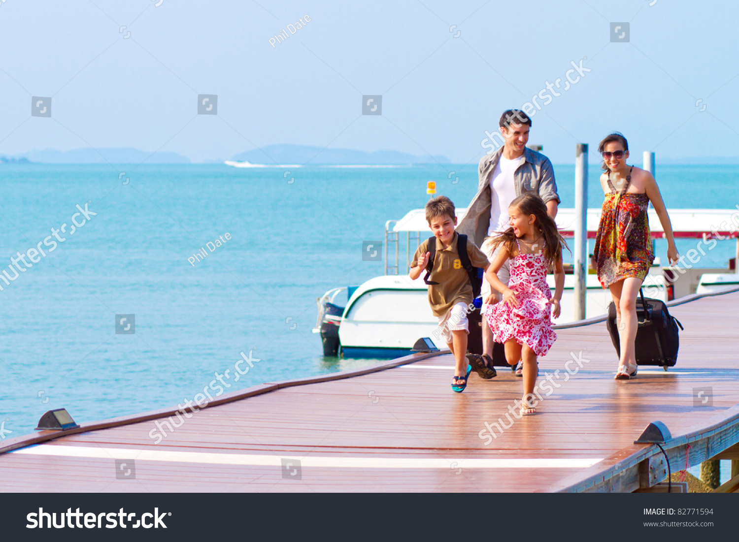 A family of 4 arriving at the resort with their luggage. #82771594