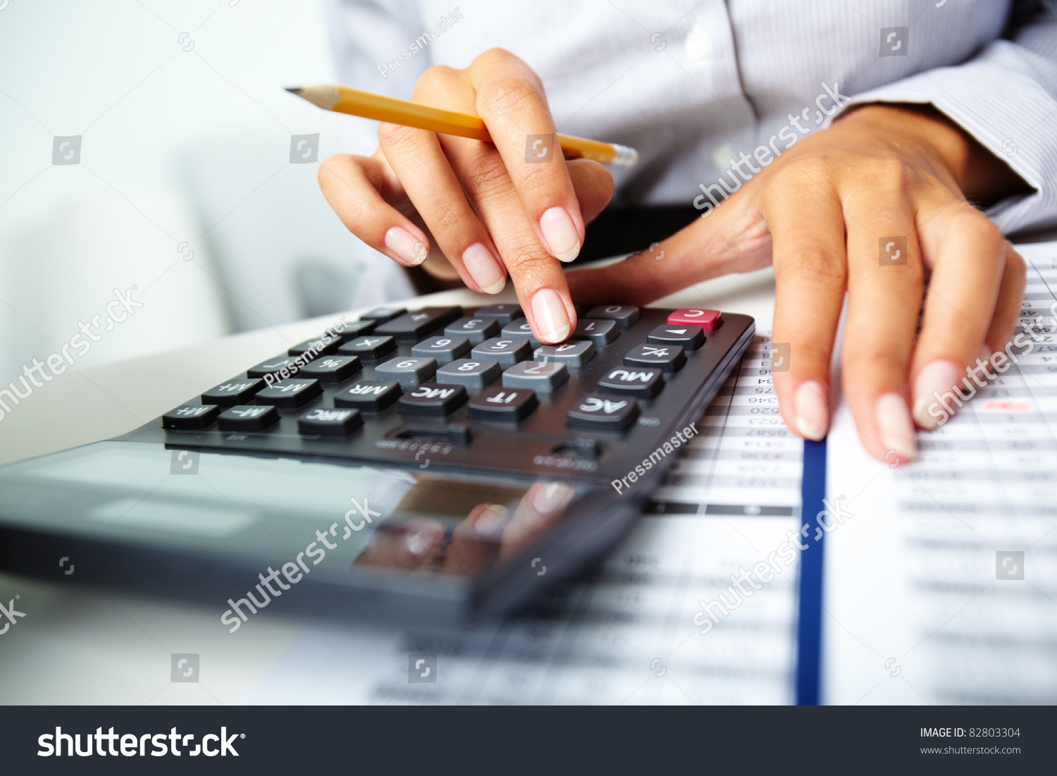Photo of hands holding pencil and pressing calculator buttons over documents #82803304