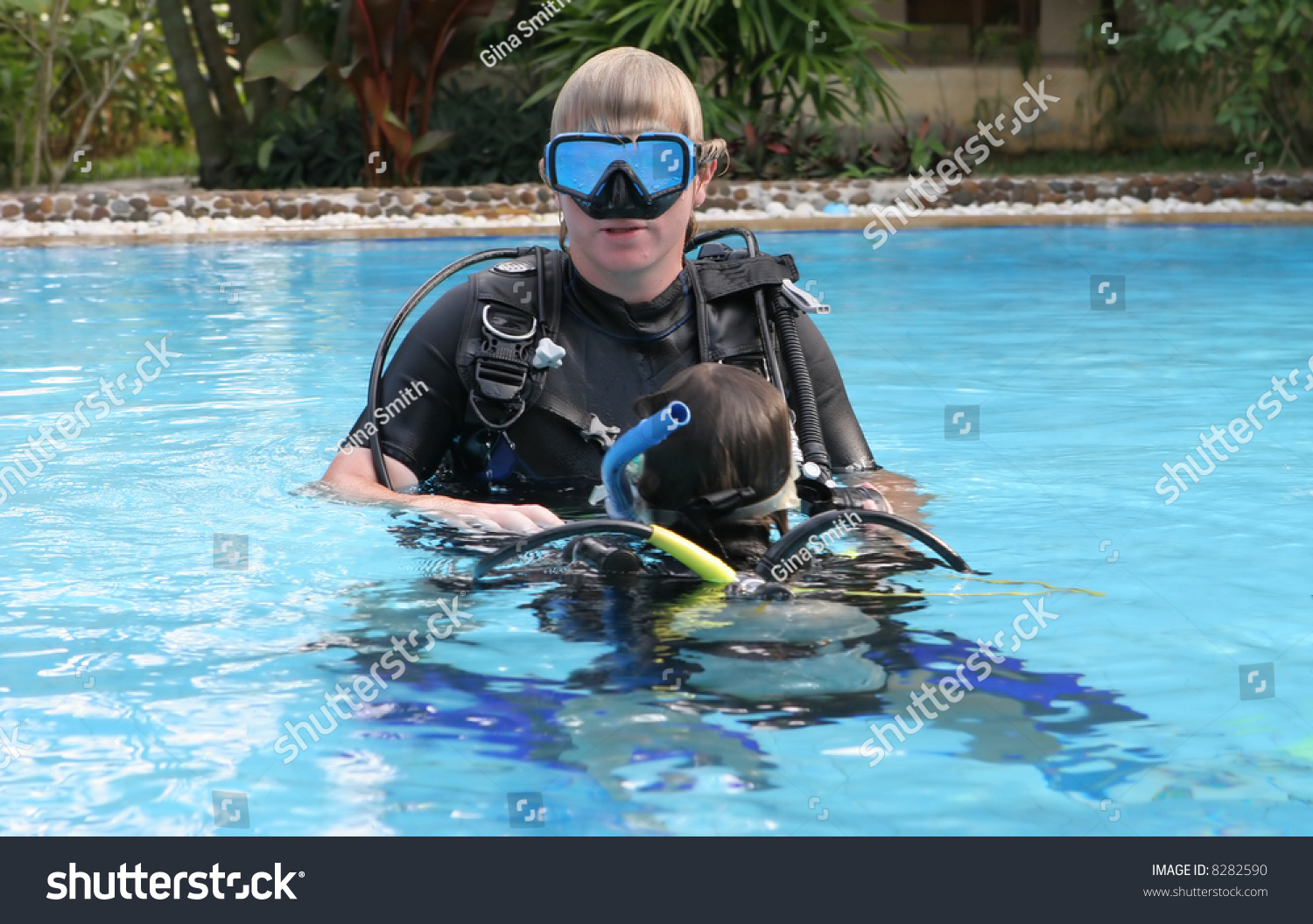 Scuba diving instructor demonstrates a skill to a student in a swimming pool. #8282590