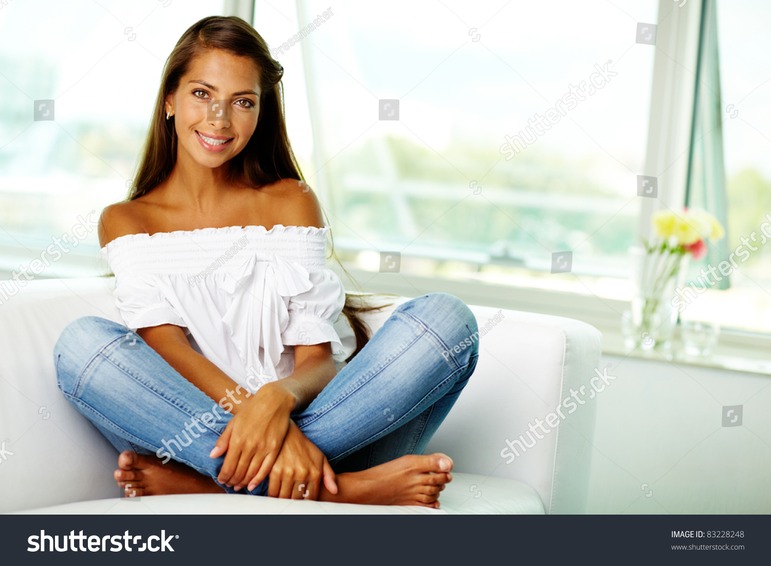 Portrait of cute brunette sitting on sofa at home #83228248