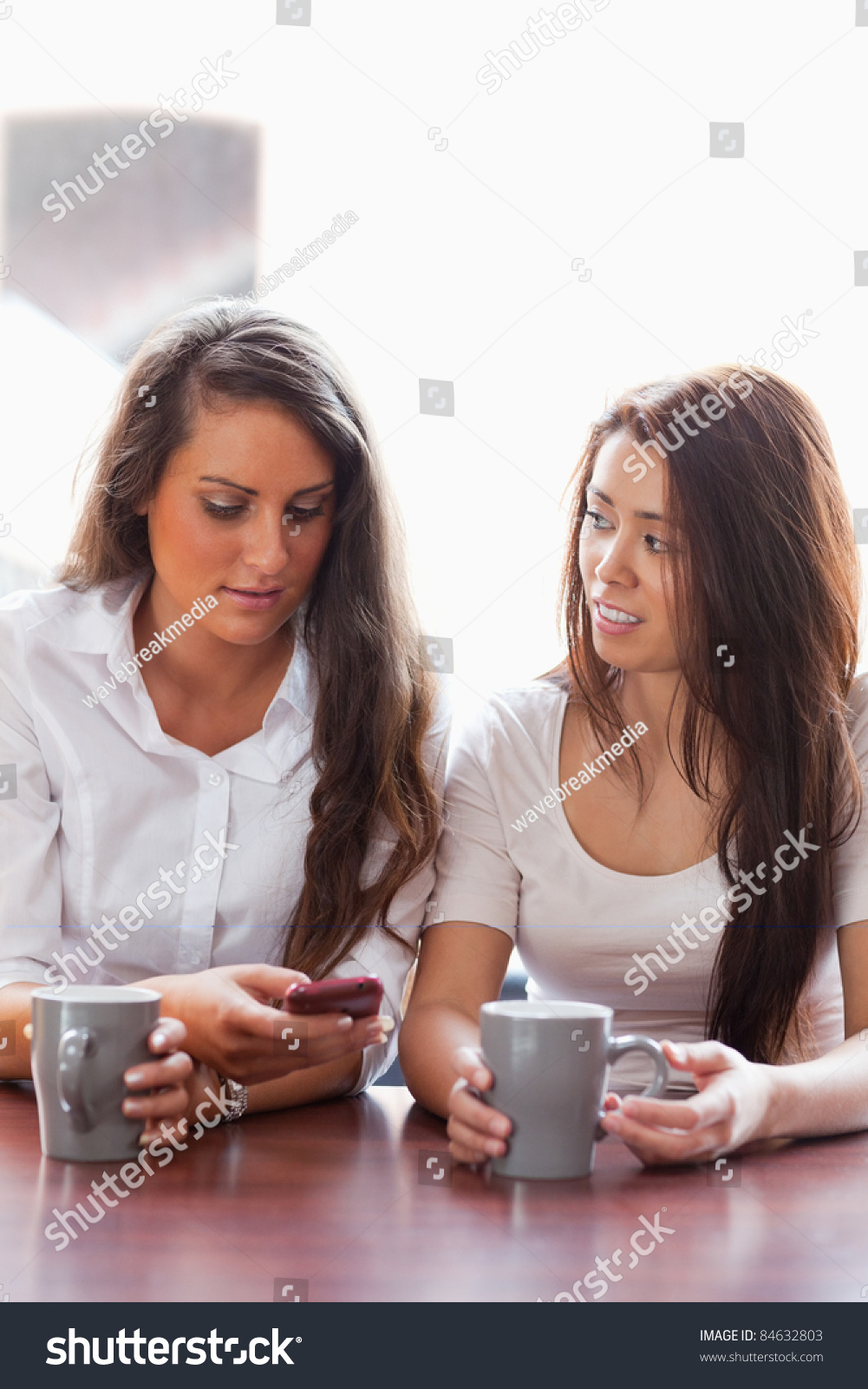 Portrait of friends looking at a smartphone while having a coffee #84632803