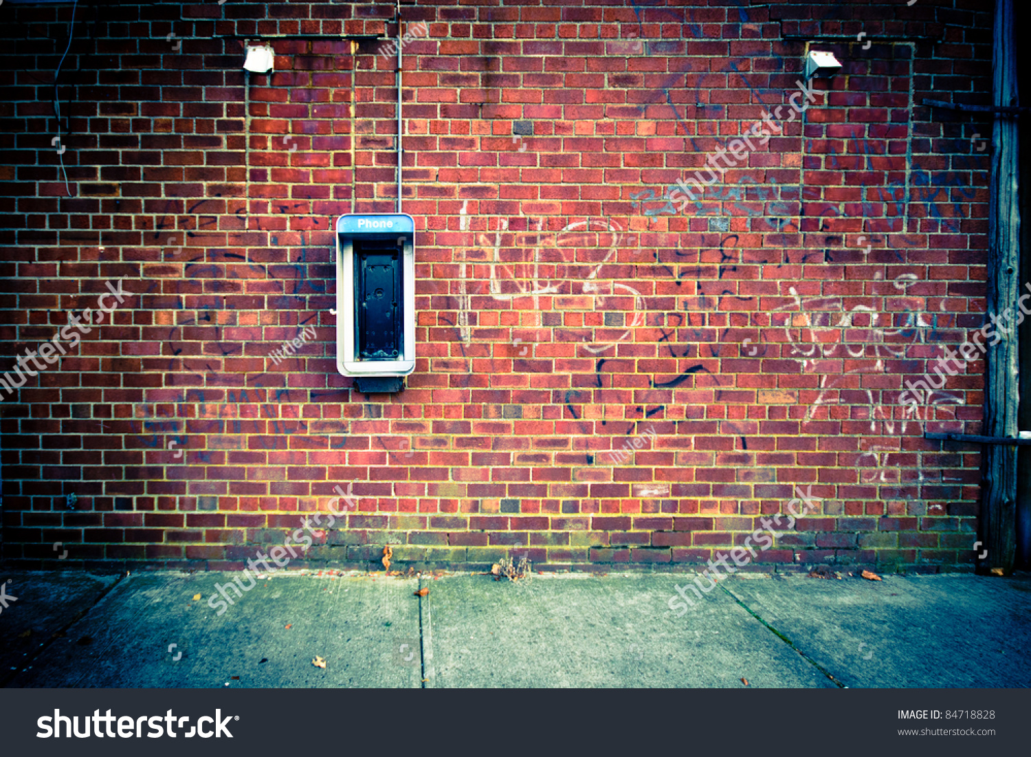 Grungy urban background of a brick wall with an old out of service payphone on it #84718828