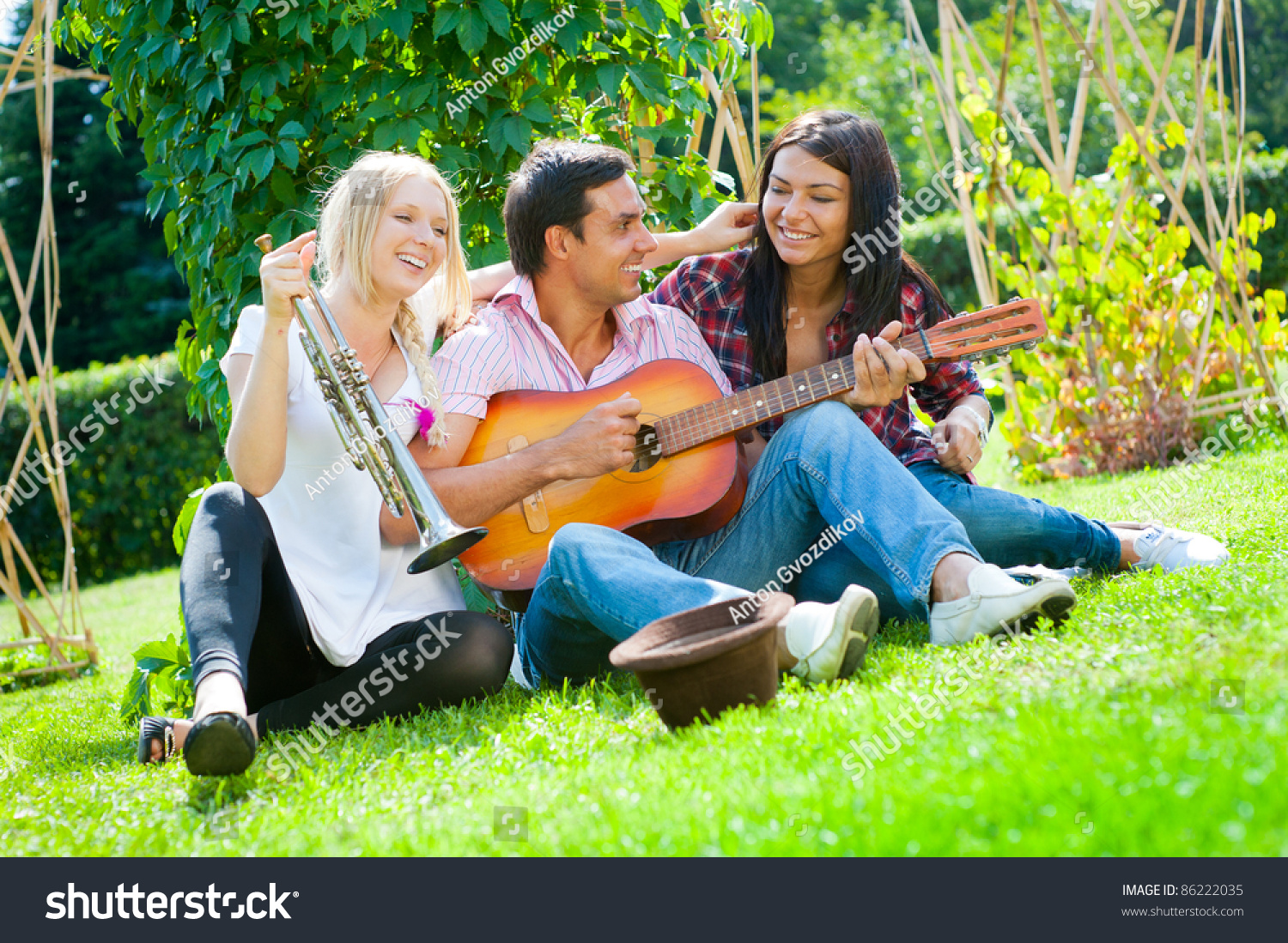Young friends play the guitar and trumpet in the park #86222035