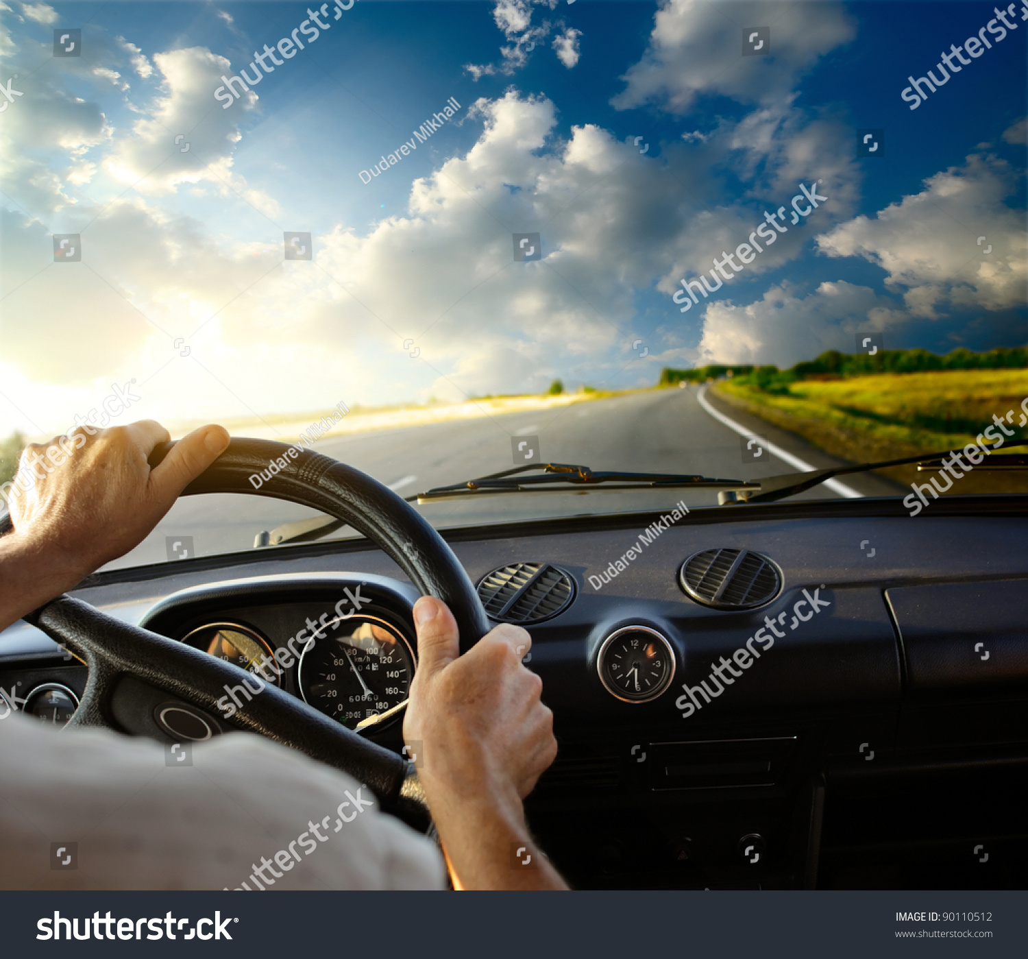 Hands of a driver on steering wheel of a car and empty asphalt road #90110512