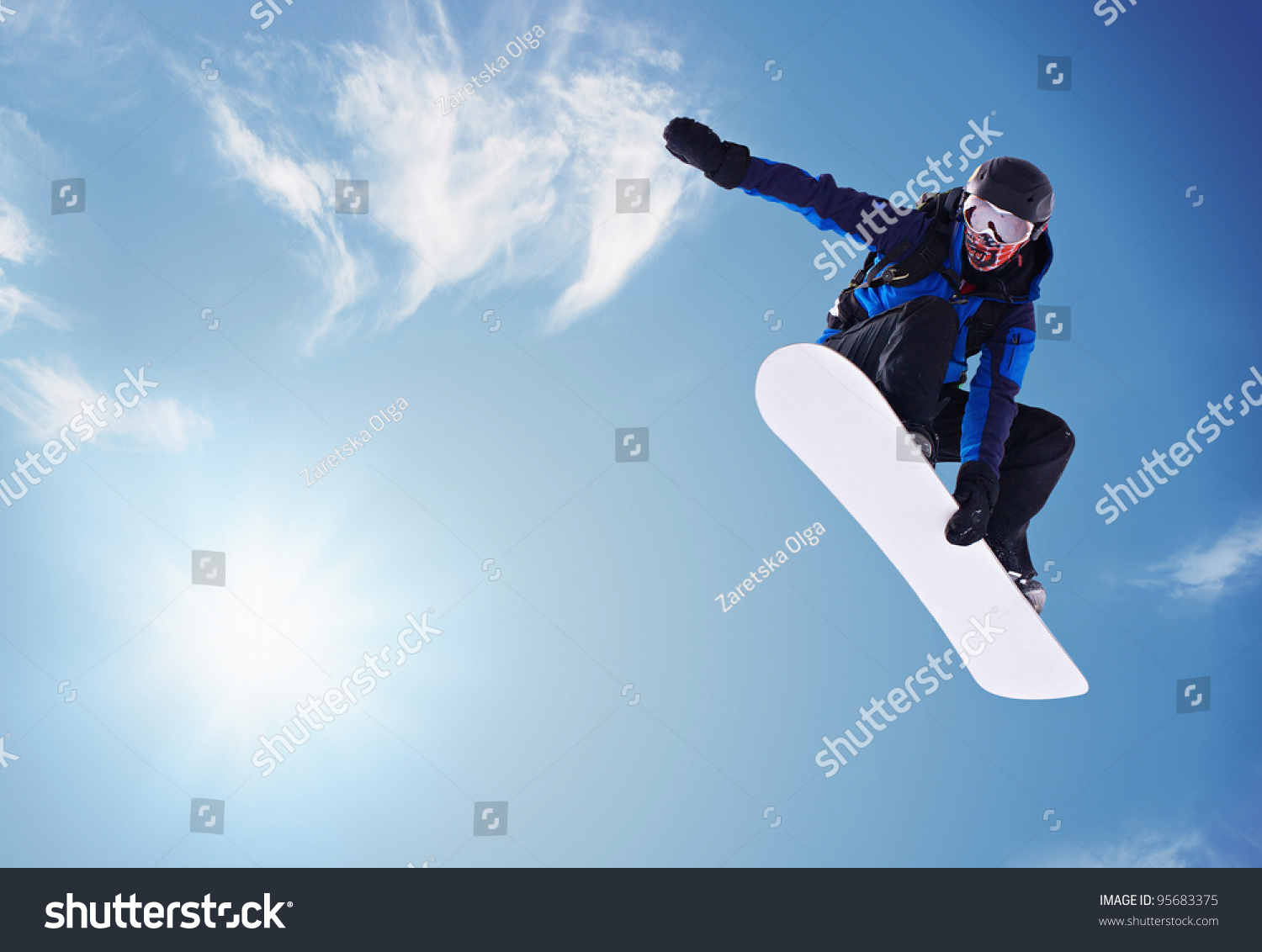 Snowboarder jumping against blue sky #95683375
