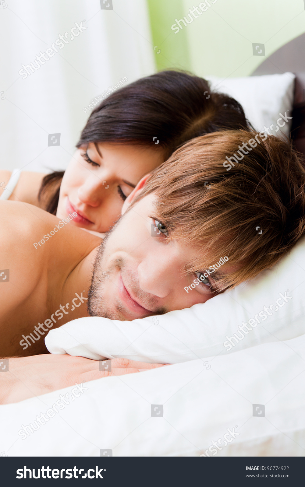 young lovely couple lying in a bed, happy smile man looking at camera, woman sleep with closed eyes #96774922