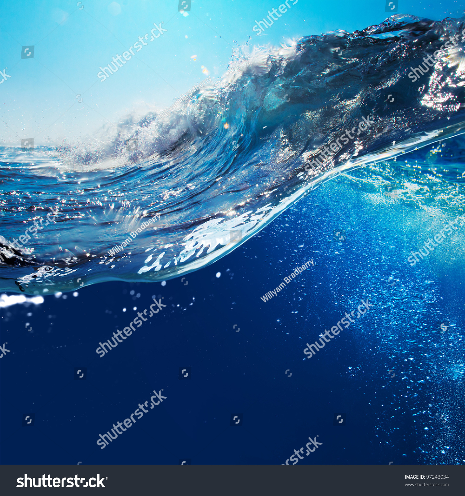 ocean-view seascape landscape with blue sky and sunlight big curly ocean wave splitted by waterline to underwater part with air bubbles #97243034