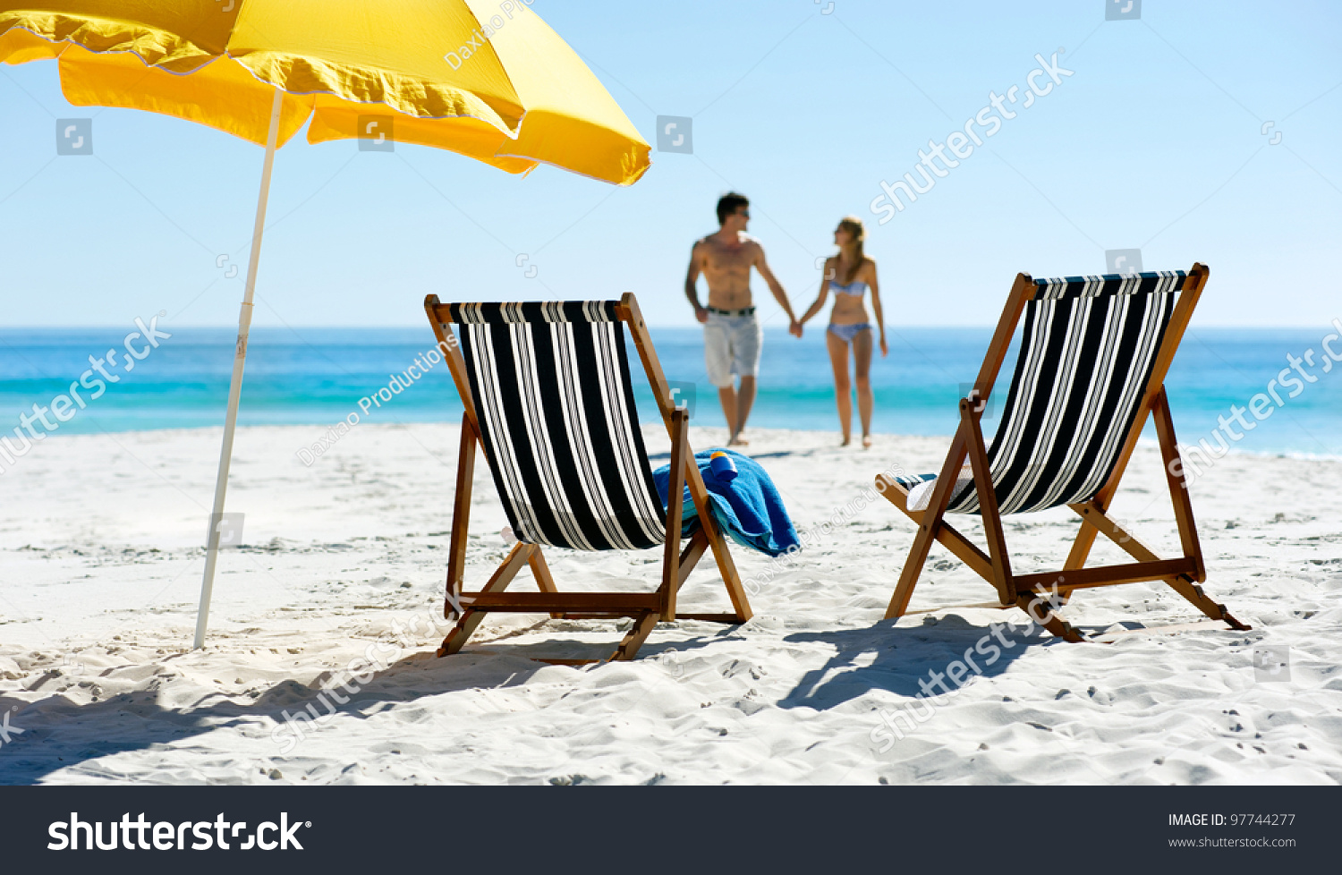Tropical summer beach holiday couple walk towards the ocean holding hands while on honeymoon vacation #97744277