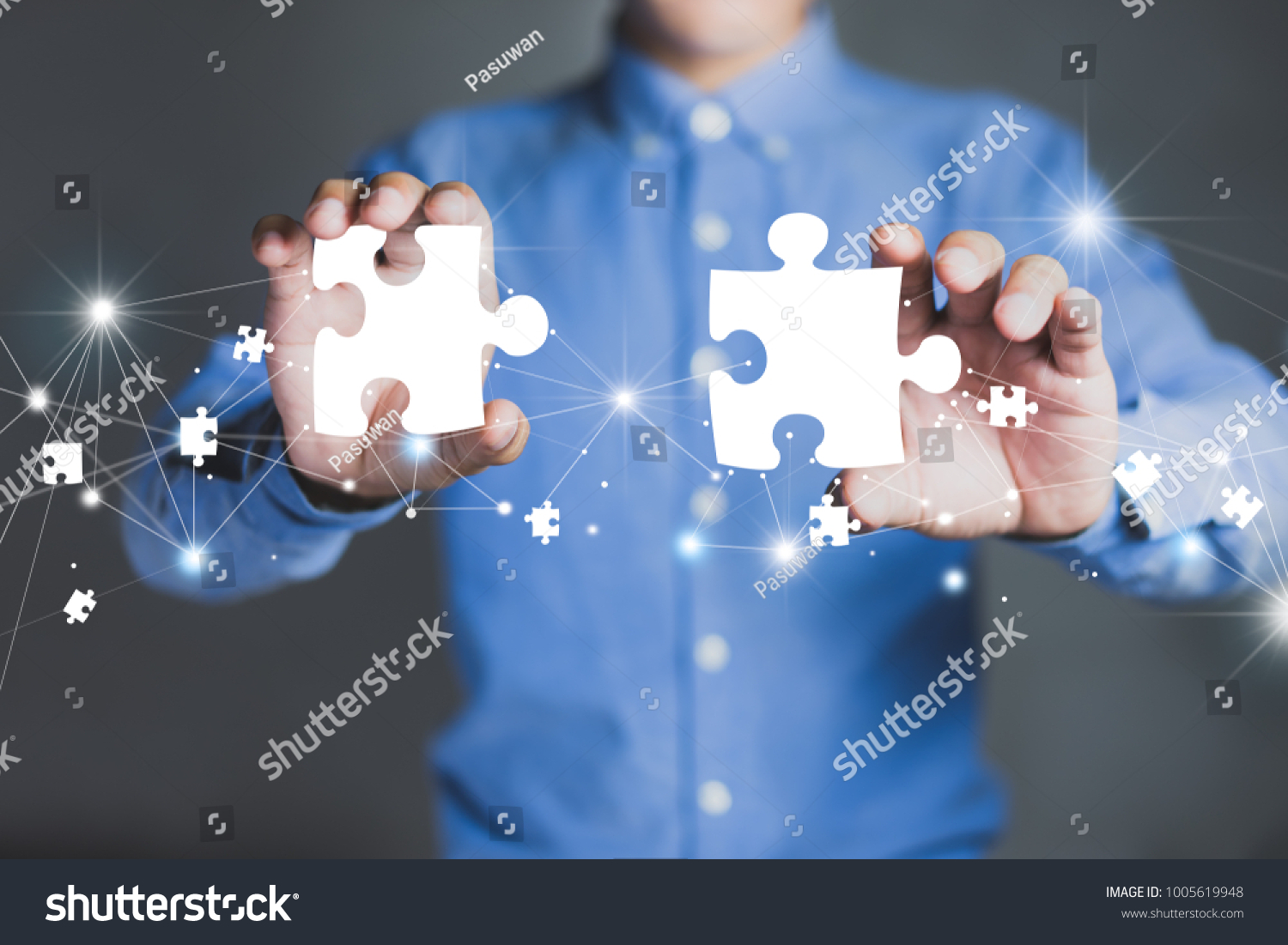 Businessman hands connecting puzzle pieces representing the merging of two companies or joint venture, partnership, Mergers and acquisition concept. #1005619948