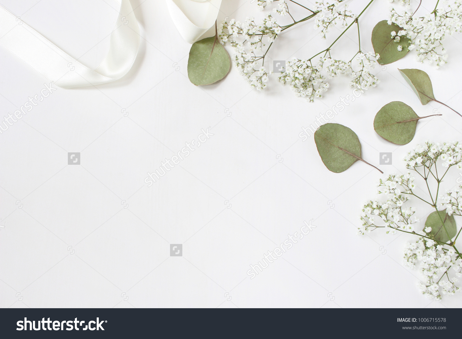 Styled stock photo. Feminine wedding desktop mockup with baby's breath Gypsophila flowers, dry green eucalyptus leaves, satin ribbon and white background. Empty space. Top view. Picture for blog. #1006715578