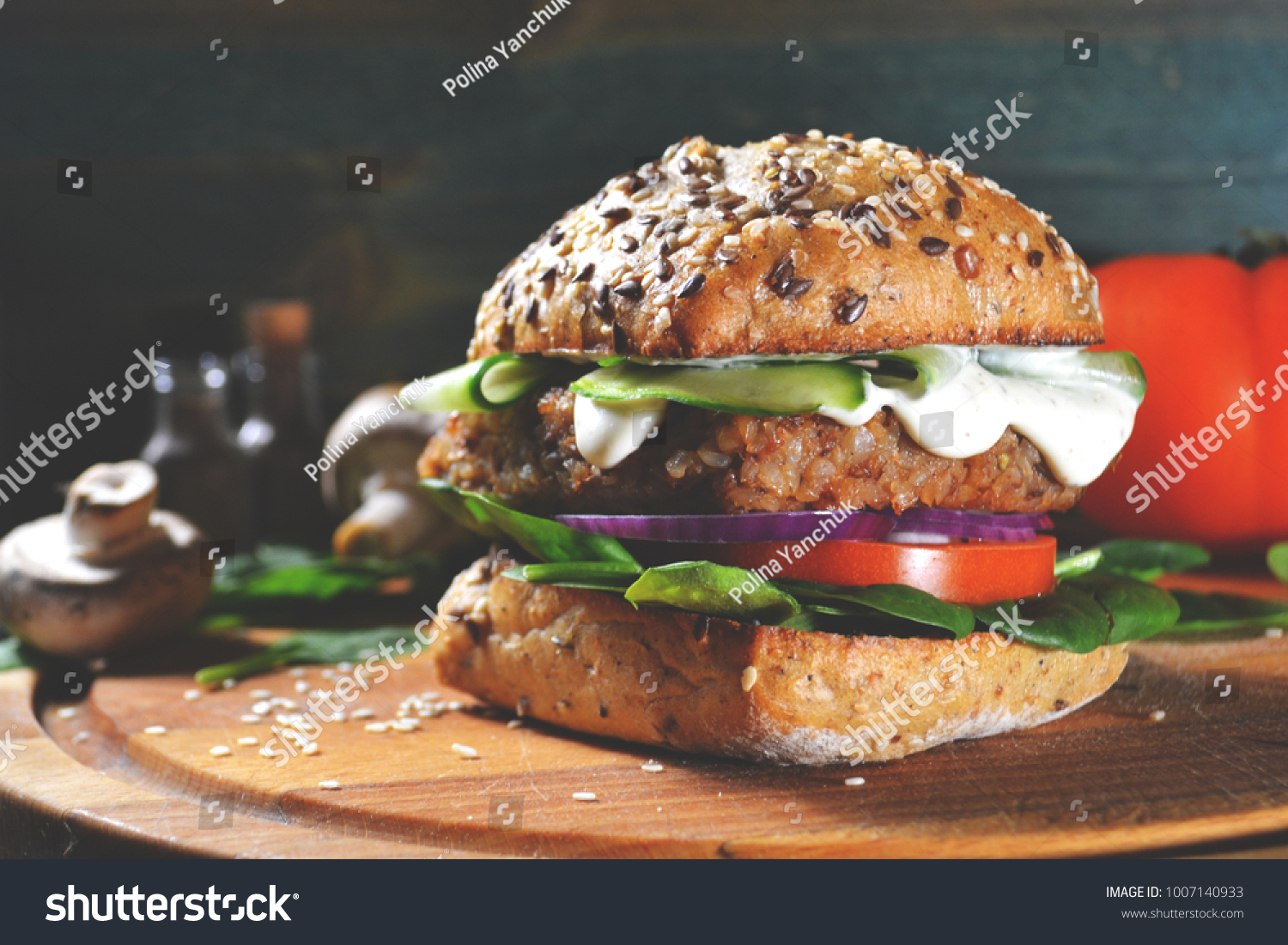 veggie, vegan burger with buckwheat, tomato, onion, vegan mayonnaise and spinach on a fresh bun with flax seeds and sesame, surrounded by spinach leaves, mushrooms, tomato, black pepper and spices. #1007140933