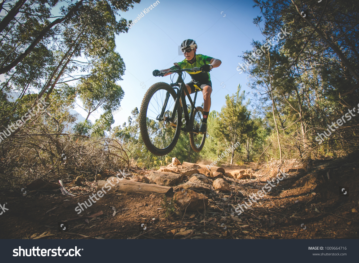 Wide angle view of a mountain biker speeding downhill on a mountain bike track in the woods #1009664716