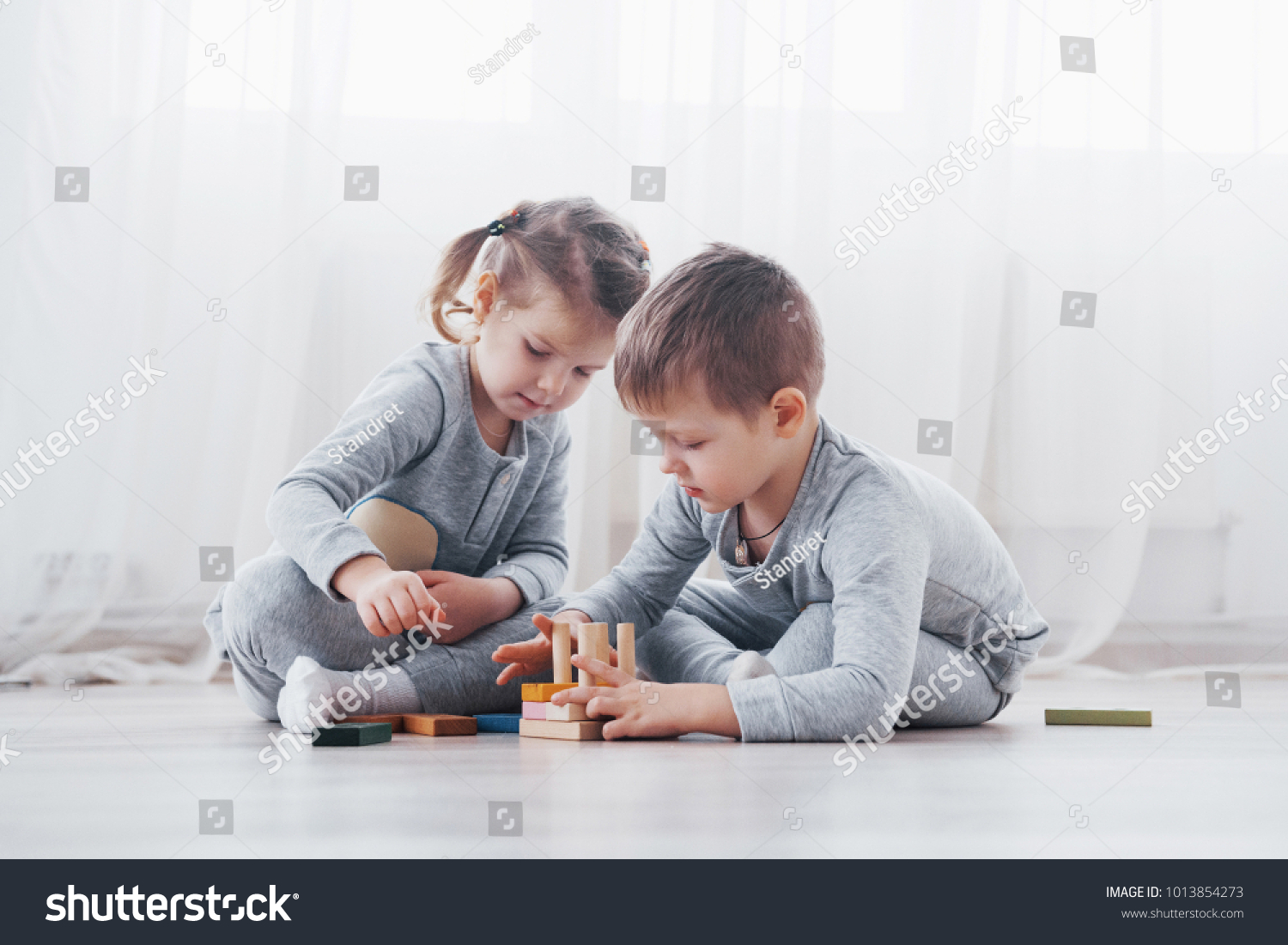 Children play with a toy designer on the floor of the children's room. Two kids playing with colorful blocks. Kindergarten educational games. #1013854273