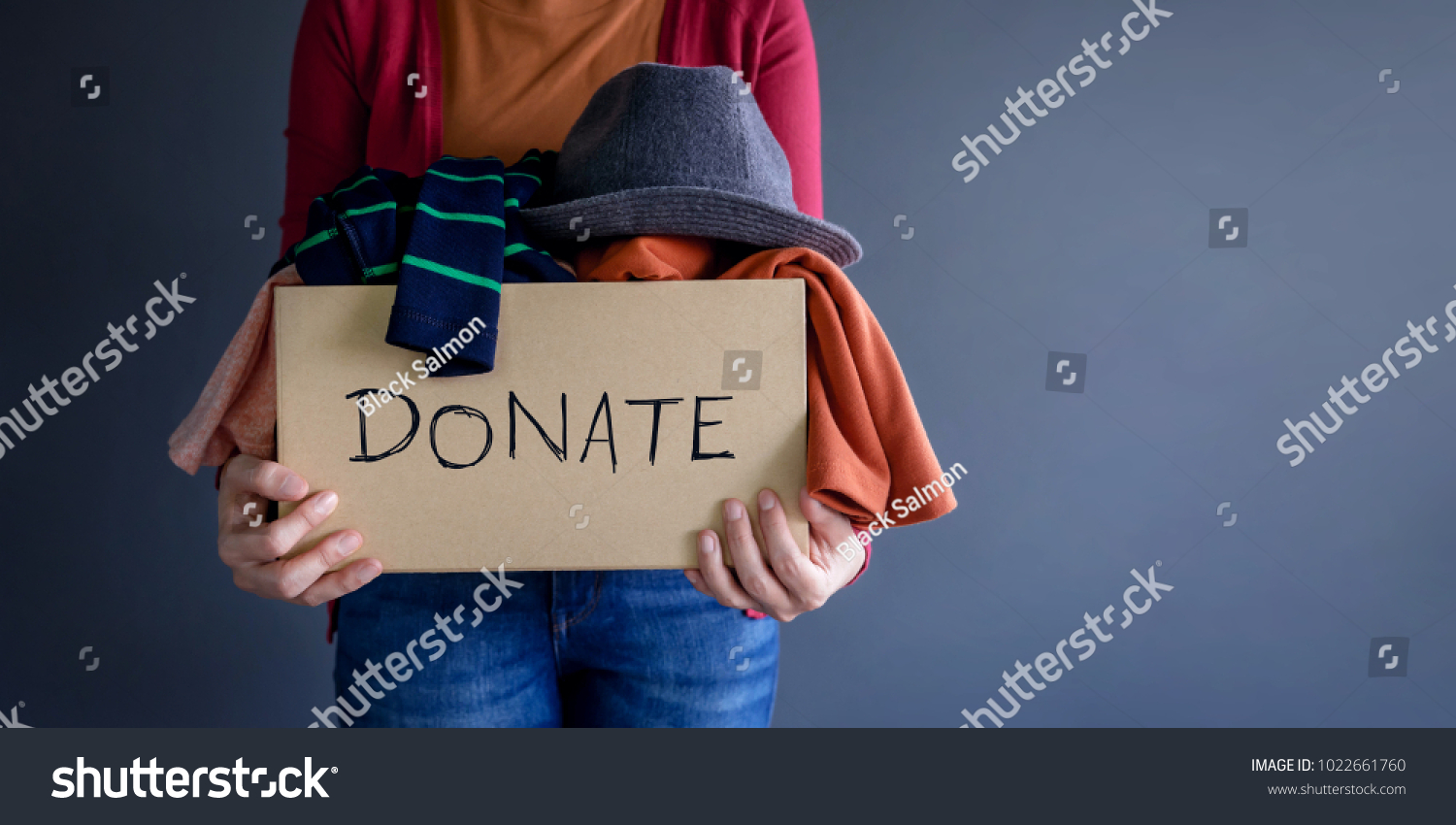Donation Concept. Woman holding a Donate Box with full of Clothes #1022661760